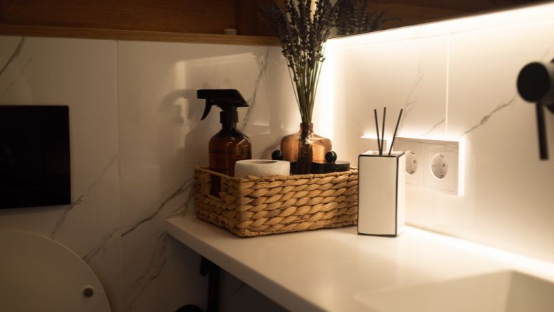Bancada de banheiro organizada com cesto de fibra natural, frascos padronizados e difusor de ambiente